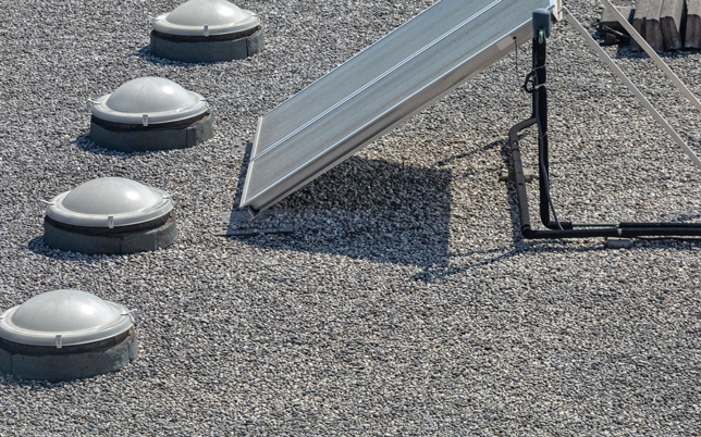 Rooftop solar panel and skylights on a gravel roof, showcasing sustainable energy and architecture design.