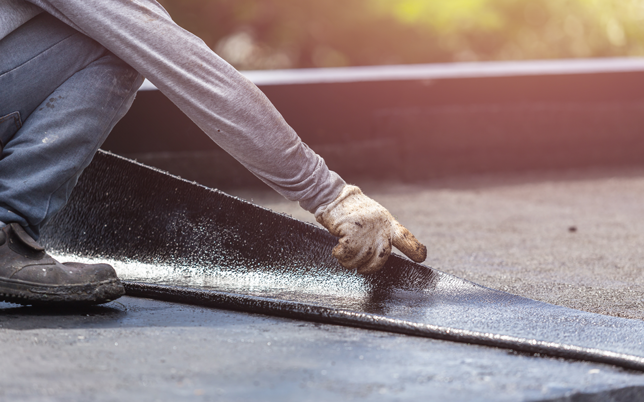 Workers laying down flat roof.